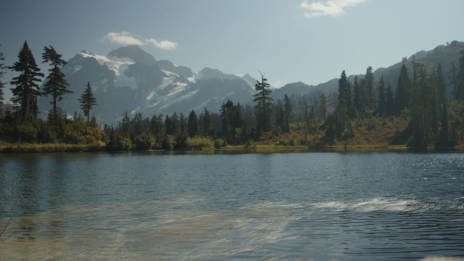 Image of a mountain with a glacier atop it, an idyllic lake in the foreground.
